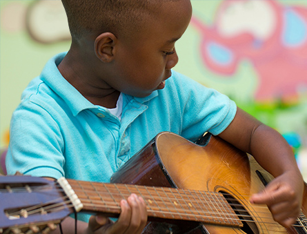 Child Practicing With a Guitar